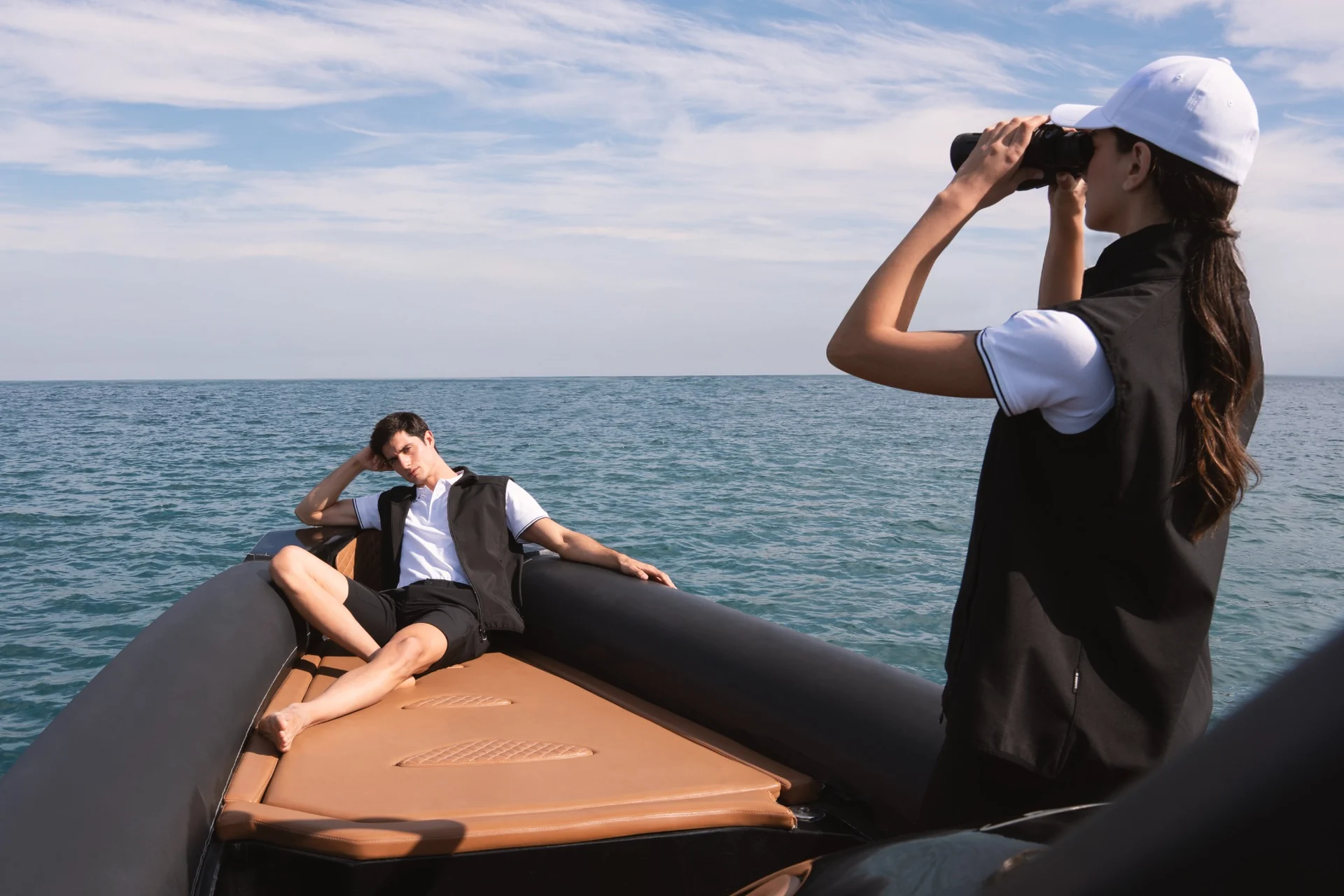 Two models in black and white nautical clothing aboard a tender on the open sea