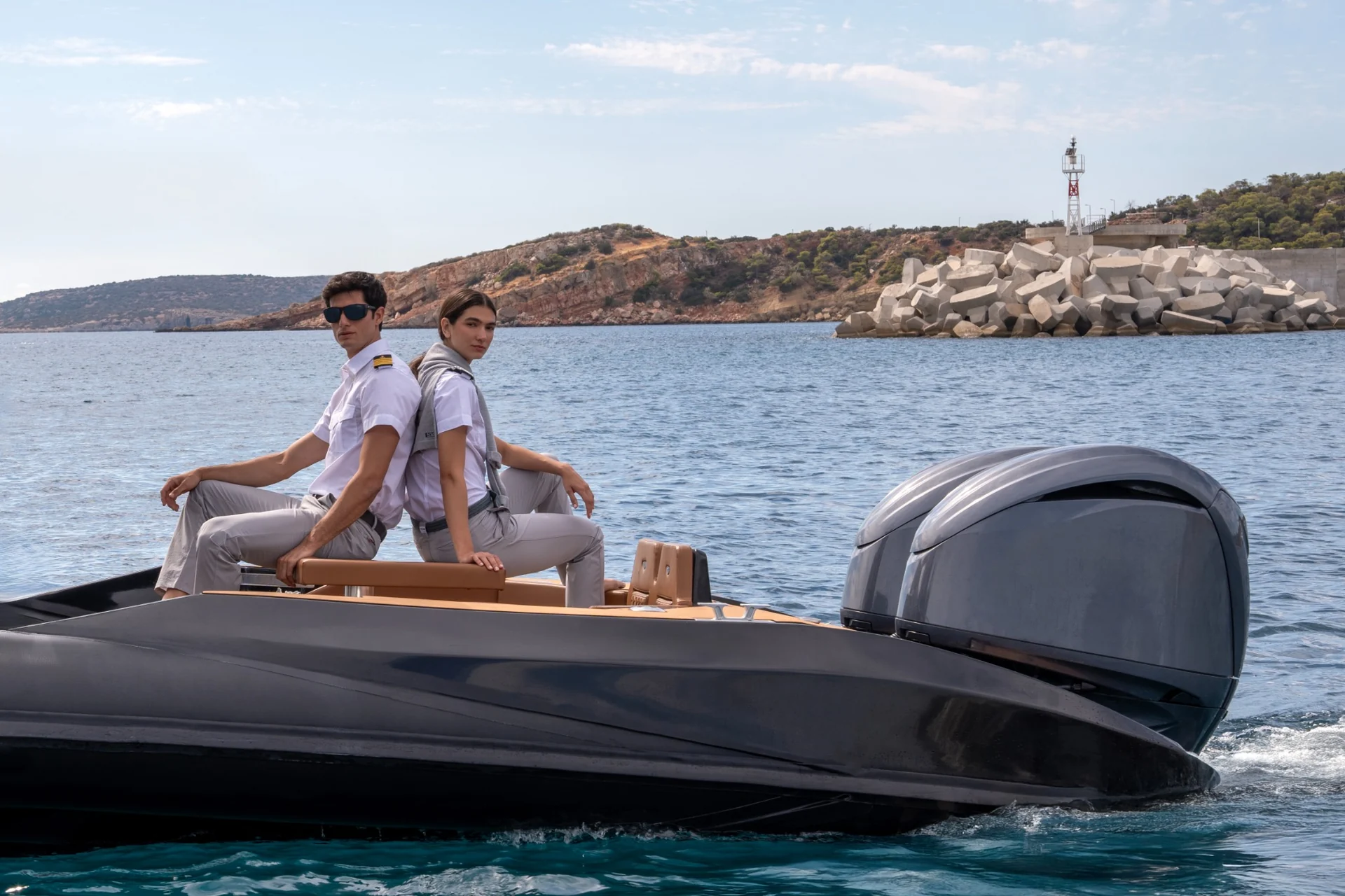 Two models in white crew shirts sitting back to back aboard a tender