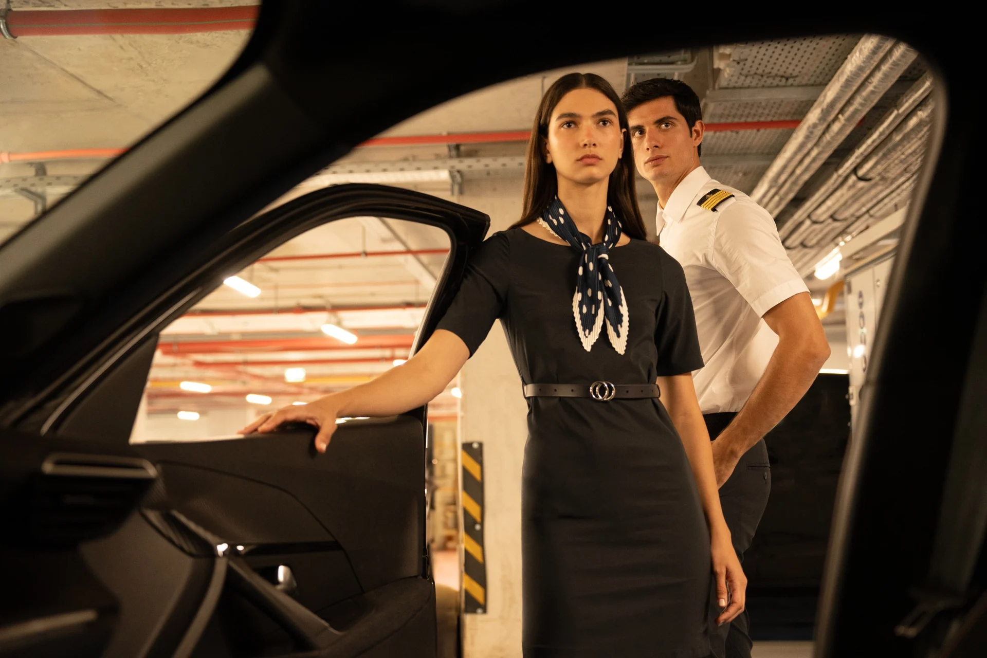 Two models in nautical uniforms framed by an open car door