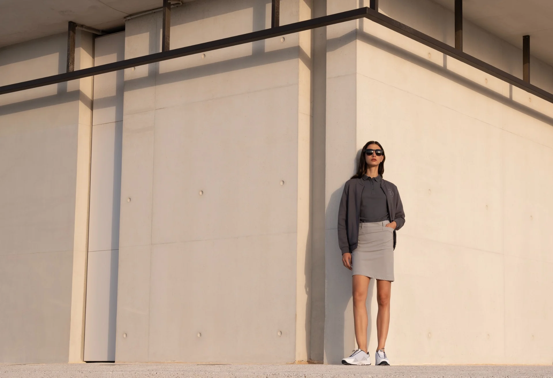 Female model in grey nautical clothing against a sunlit architectural wall