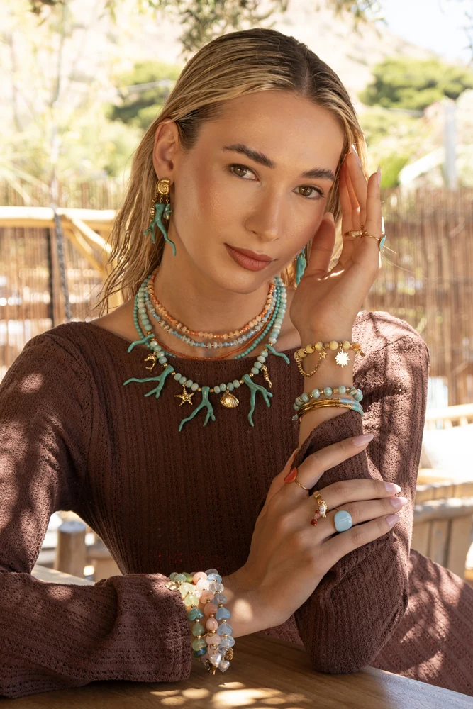 Portrait in a brown knit top with turquoise jewellery in dappled sunlight