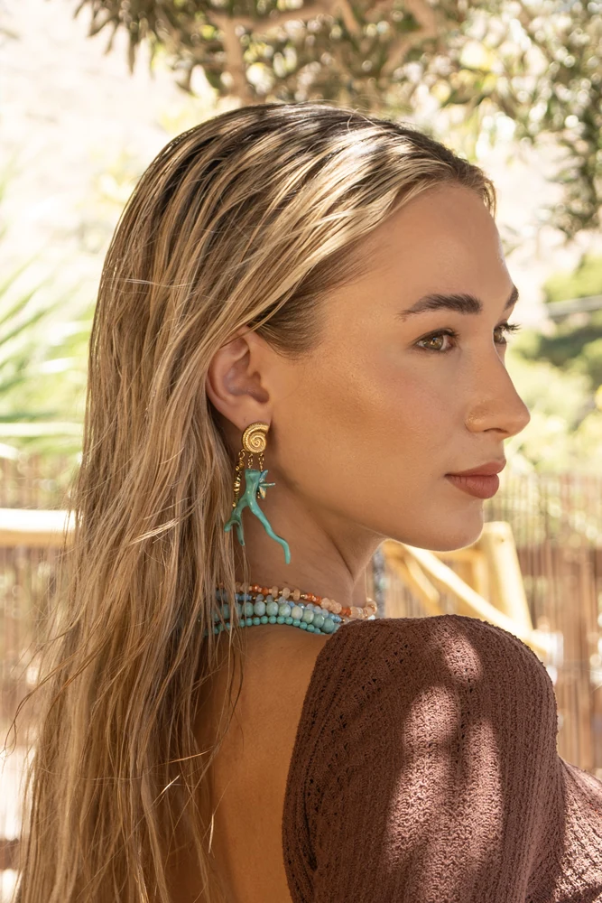 Profile portrait with turquoise coral-shaped earrings and layered beaded necklaces