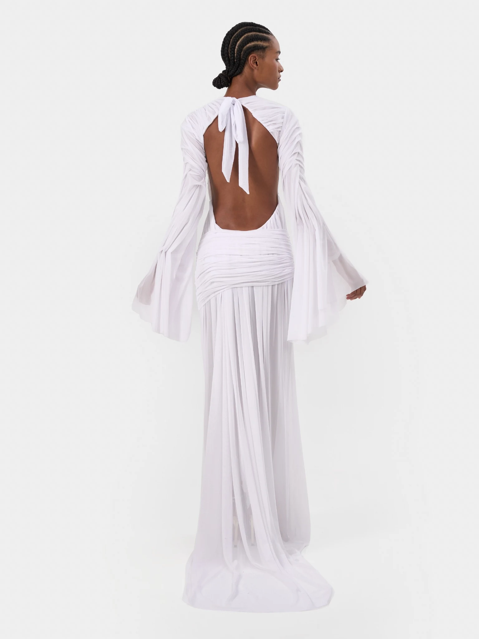 Back view of a white bridal gown with an open back and flowing sleeves