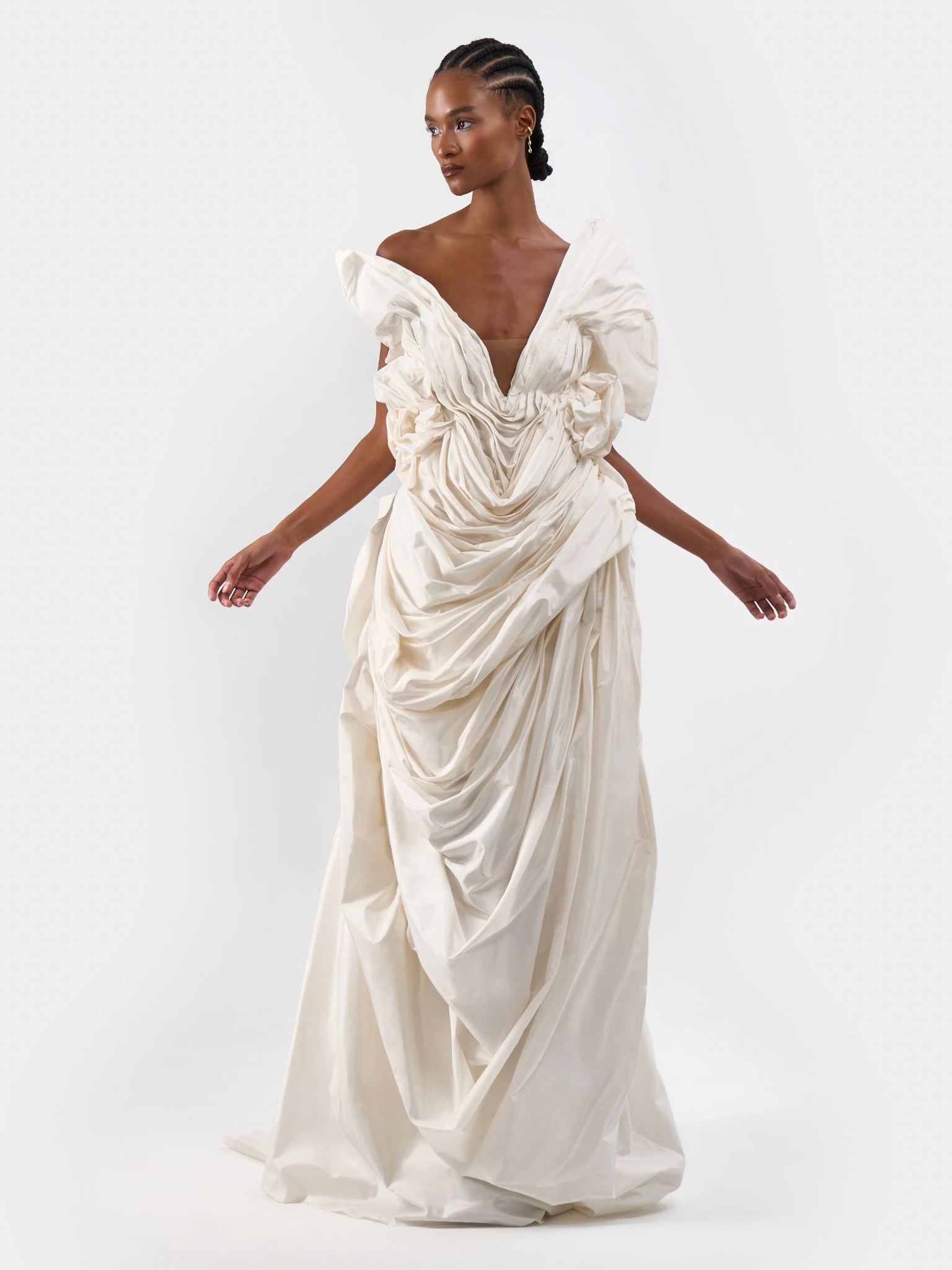 Front view of a model in a sculptural ivory bridal gown with gathered fabric