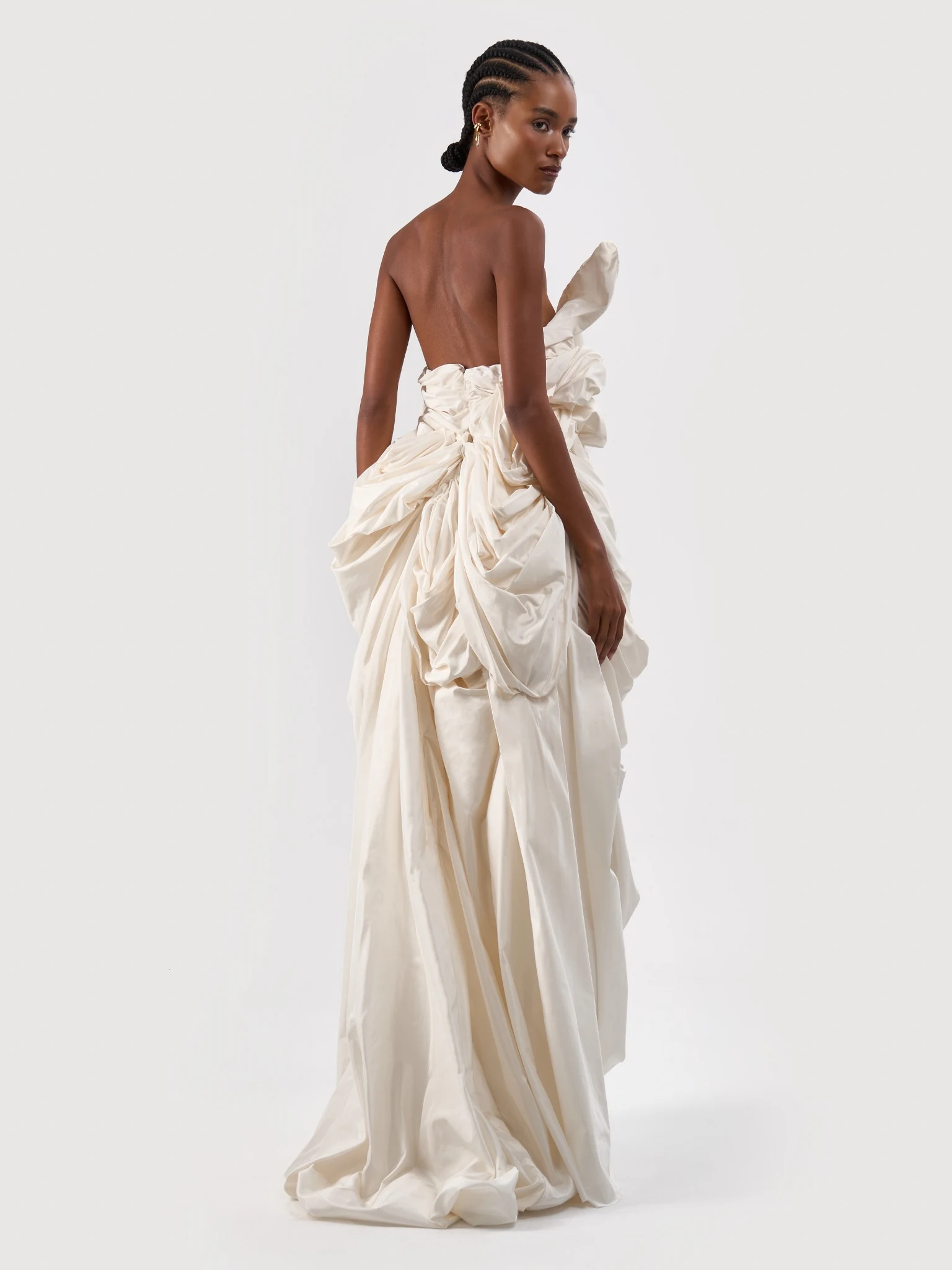 Back view of an ivory bridal gown with sculptural folds and a long skirt