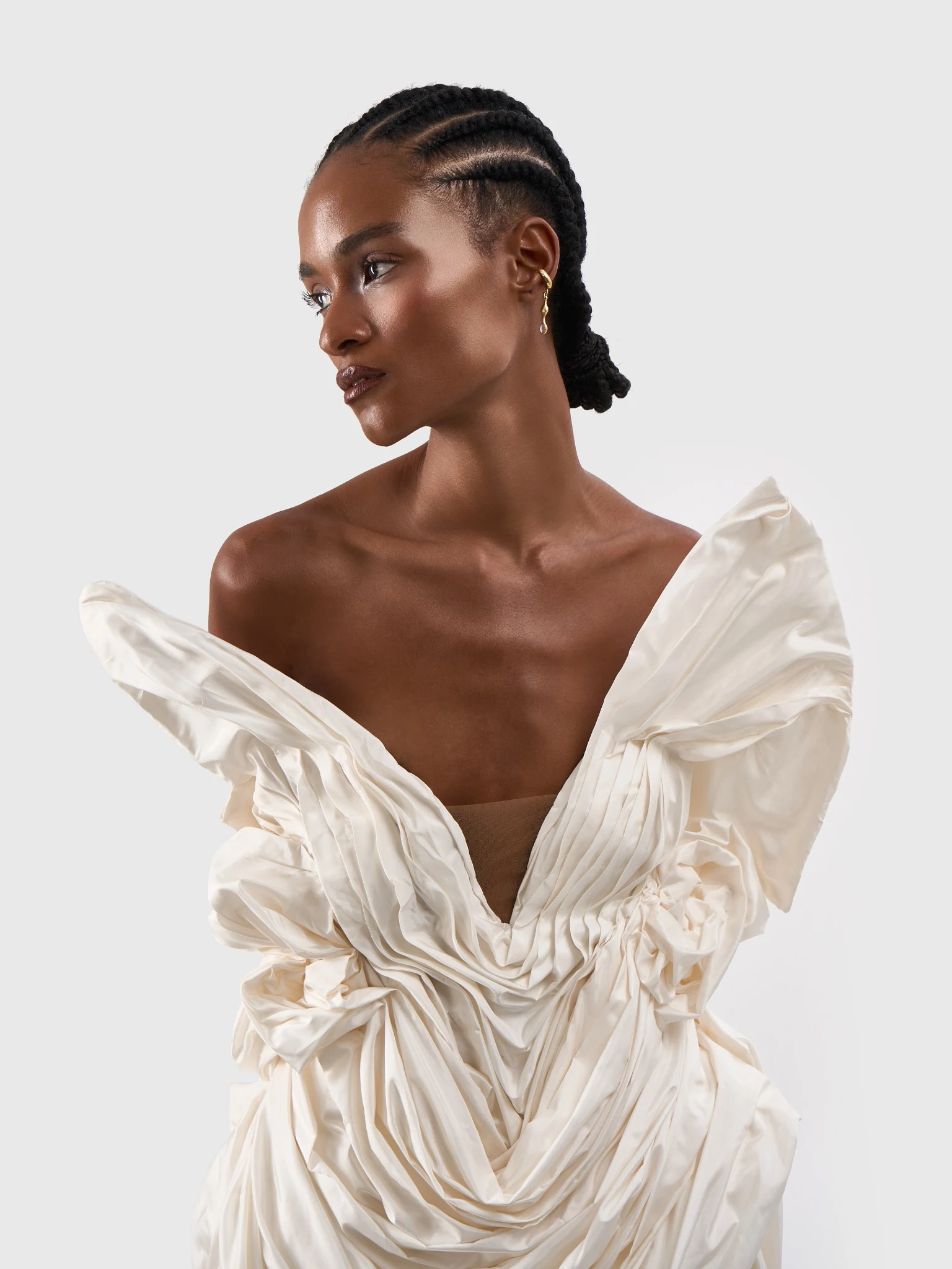 Close studio portrait of a model in a sculptural ivory bridal gown