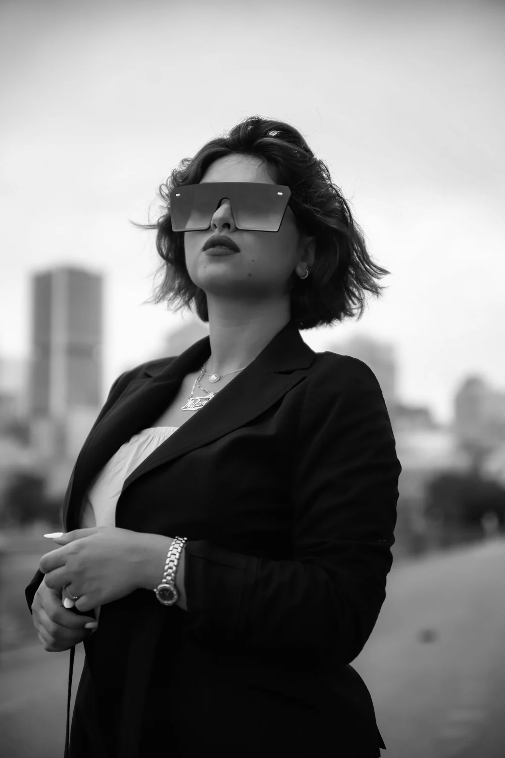 Fashion-influenced outdoor portrait of a woman in a black blazer against an urban skyline