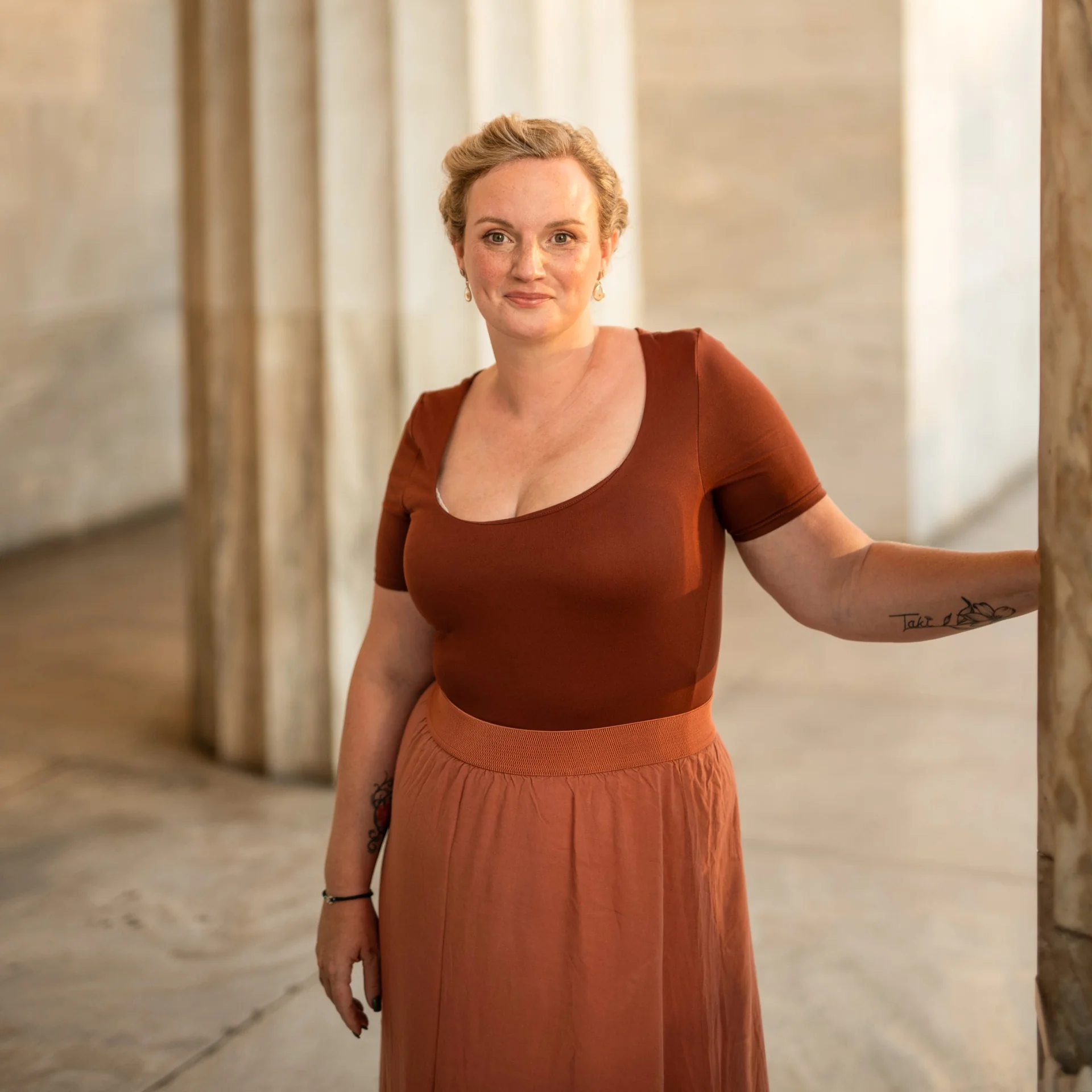 A relaxed portrait of Melina beside a pale stone wall