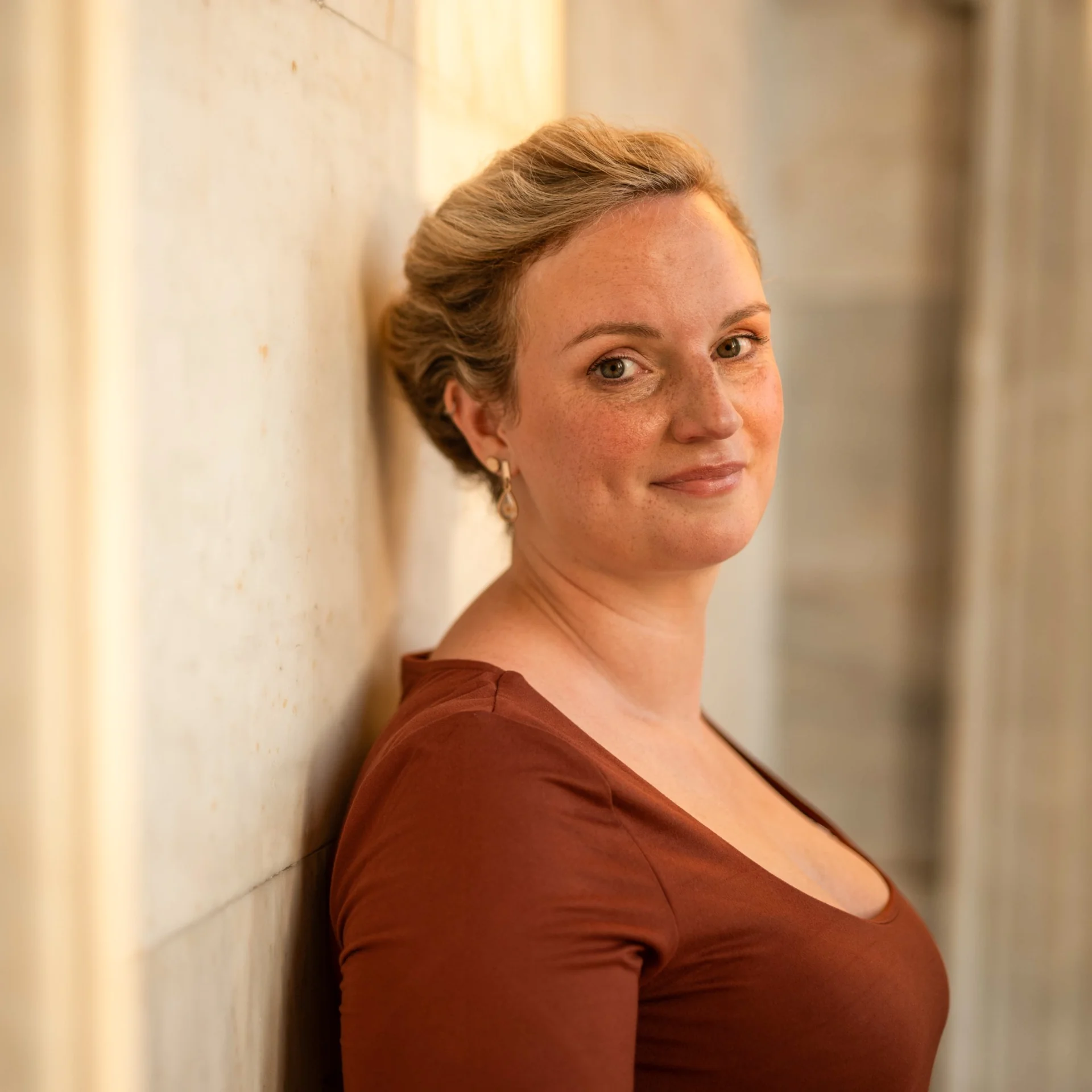 Close portrait of Melina in warm light, with softly focused columns behind her