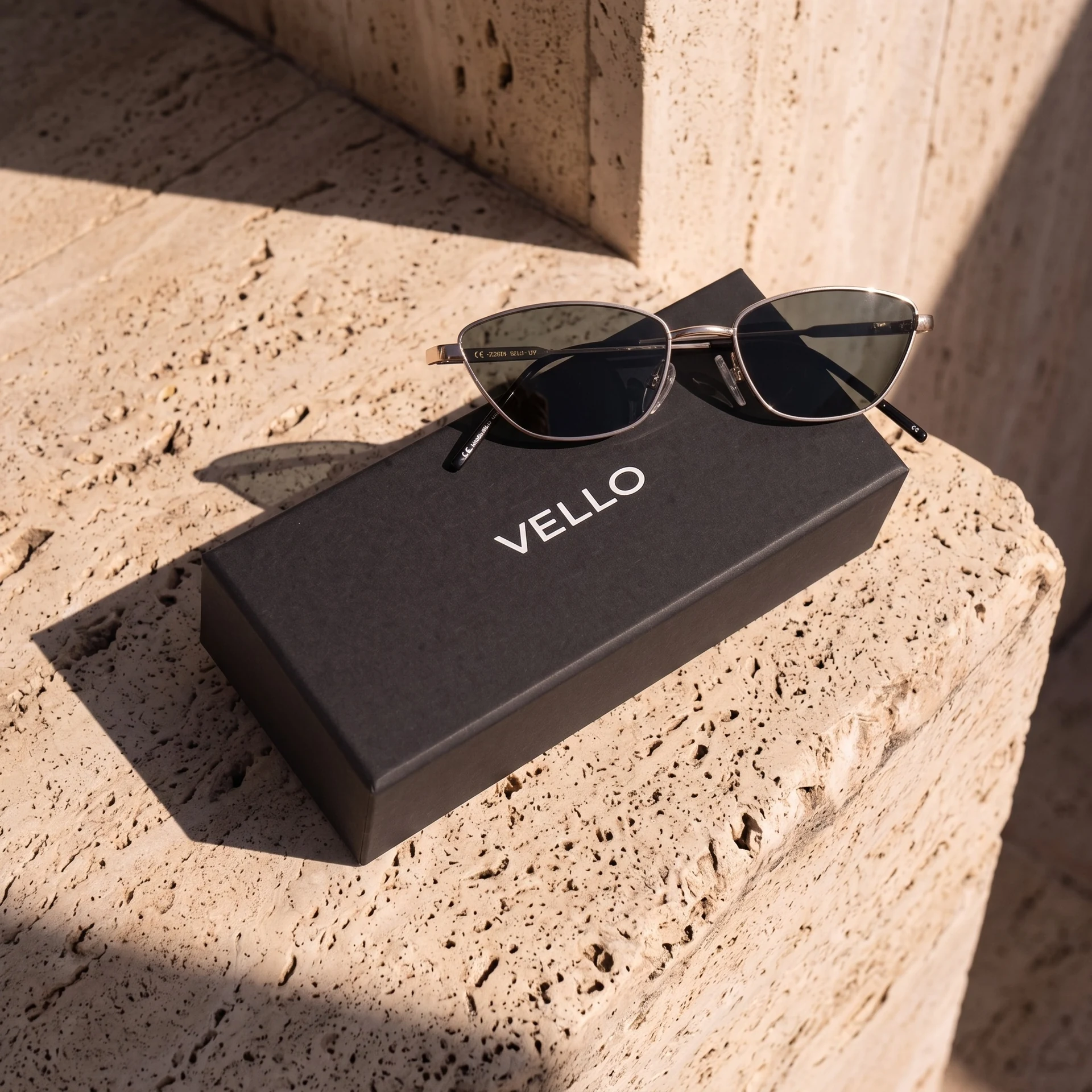 Slim metal Vello sunglasses resting on a black branded case